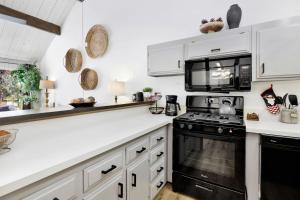 uma cozinha com armários brancos e electrodomésticos pretos em 2125-Switzerland Slopes townhouse em Big Bear Lake