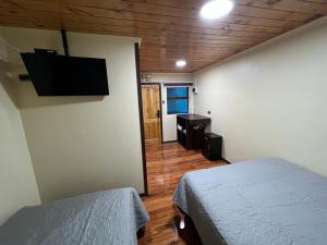 a bedroom with two beds and a flat screen tv at Hospedaje Santa Barbara in Santa Bárbara
