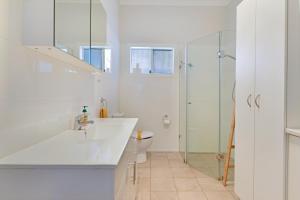 ein weißes Bad mit einem Waschbecken und einer Dusche in der Unterkunft Cottage on Lords in Orange