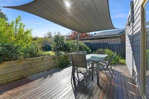 eine Terrasse mit einem Tisch und Stühlen auf einer Holzterrasse in der Unterkunft Cottage on Lords in Orange