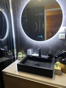 uma casa de banho com um lavatório preto e um espelho em Le Chalet Gîte de Dordogne em Saint-Pardoux-la-Rivière