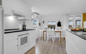 una cocina con armarios blancos y una mesa con sillas. en 3 Bedroom Gorgeous Home In Haderslev, en Haderslev