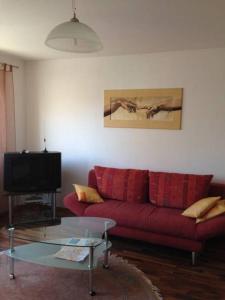 ein Wohnzimmer mit einem roten Sofa und einem TV in der Unterkunft Apartment Nürnberg City-Center in Nürnberg