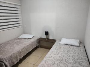 1 Schlafzimmer mit 2 Betten, einem Nachttisch und einem Fenster in der Unterkunft Excelente Departamento céntrico. in Guadalajara