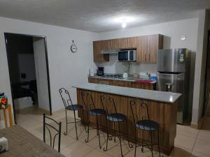 a kitchen with a counter with chairs and a refrigerator at Excelente Departamento céntrico. in Guadalajara