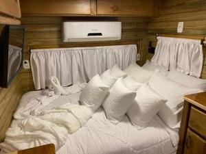 a large white bed with pillows in a room at Chale Sobre Rodas Spa Exclusive - Localizado Próximo do Centro in Canela