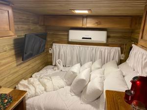 uma cama com almofadas brancas num quarto em Chale Sobre Rodas e Spa Exclusive - Localizado Próximo do Centro em Canela