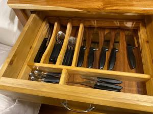 un tiroir en bois rempli de couteaux et de fourchettes dans l'établissement Chale Sobre Rodas e Spa Exclusive - Localizado Próximo do Centro, à Canela