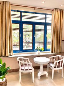 2 sillas y una mesa en una habitación con ventanas en Hi Hợp Yến Homestay, en Hoi An
