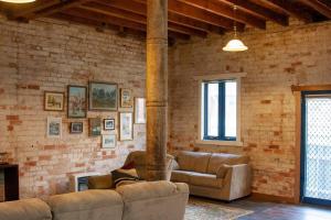 a living room with two couches and a brick wall at 1885 Warehouse Apartment in Tumbarumba
