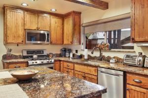een keuken met houten kasten en granieten aanrechtbladen bij 2080-Eagle Point Lodge home in Big Bear Lake