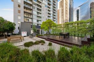 a garden with a bench and a table in a city at Exclusive Stays - Rivergarden in Melbourne