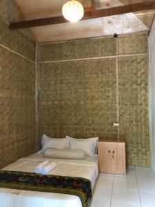 a bed in a room with a brick wall at Azka Homestay in Kuta Lombok