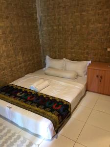 a bed with white sheets and pillows in a room at Azka Homestay in Kuta Lombok