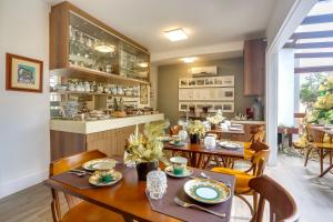 a dining room with tables and chairs and a kitchen at Nova Pousada dos Chás in Florianópolis
