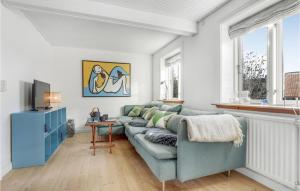 uma sala de estar com um sofá azul e uma televisão em 2 Bedroom Awesome Home In Rnne em Rønne