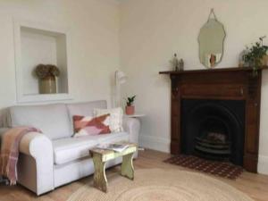 sala de estar con sofá blanco y chimenea en Randell Cottage - Adelaide Hills - Cosy Rustic Hideaway, en Gumeracha