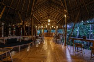 restauracja ze stołami i krzesłami oraz drewnianą podłogą w obiekcie Bila Penida Resort & Farm w mieście Nusa Penida