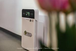 a small refrigerator with a clock on it next to a vase of flowers at Knight Alley Hotel in Taiping