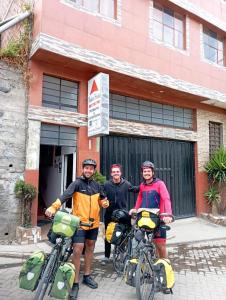 três homens em pé em frente a um edifício com as suas bicicletas em Andes Hostel em Huaraz