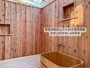a bathroom with a wooden wall with a tub at Yatsugatake Little Village Hotel in Hara