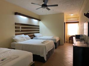 Habitación de hotel con 2 camas y ventilador de techo. en SKY INN en Caye Caulker
