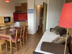 ein Wohnzimmer und eine Küche mit einem Sofa und einem Tisch in der Unterkunft Appartement Auris, 1 pièce, 3 personnes - FR-1-297-326 in Auris
