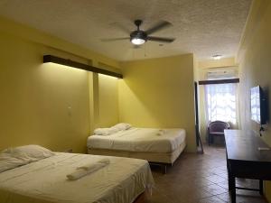 um quarto com 2 camas e uma ventoinha de tecto em SKY INN em Caye Caulker