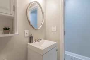 bagno bianco con lavandino e specchio di Baltimore's Home Away From Home apts a Baltimora