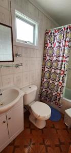 ein Badezimmer mit einem WC, einem Waschbecken und einem Duschvorhang in der Unterkunft Casa Hospedaje Costanera in Puerto Natales
