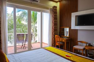 Habitación de hotel con cama y puerta corredera de cristal en Sun Viet Resort Phu Quoc, en Phu Quoc