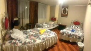 a room with two beds and a room with two tables at Hostal Jora Continental in Cotacachi