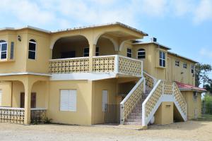 a large yellow house with a balcony and stairs at Harada Inn and Suites in Hopkins