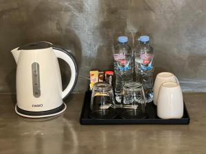 eine Kaffeemaschine mit Wasserflaschen und Gläsern auf einem Tablett in der Unterkunft The Passion Nest - SHA Plus Certified in Phuket
