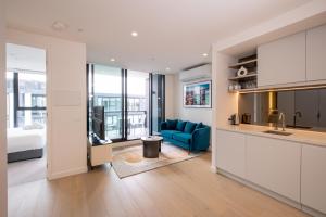 a kitchen and a living room with a blue couch at The Marker Apartments Melbourne in Melbourne