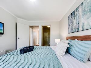1 dormitorio con 1 cama grande con sábanas azules y blancas en Seachange Apartments Merimbula en Merimbula
