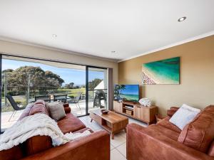 a living room with two couches and a tv at Seachange Apartments Merimbula in Merimbula