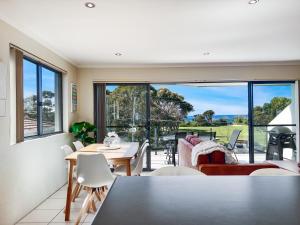 a living room with a table and chairs and a large window at Seachange Apartments Merimbula in Merimbula
