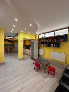 a kitchen with yellow walls and red chairs and a table at Hostel Jeal in Batumi