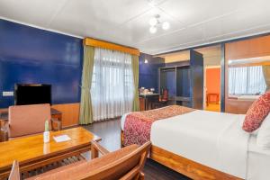 a hotel room with a bed and a table and a desk at Summit Tashi Ghang Heritage Resort in Pelling