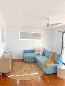 a living room with a blue couch and a rug at Lammermoor Lodge Holiday Home Yeppoon in Yeppoon