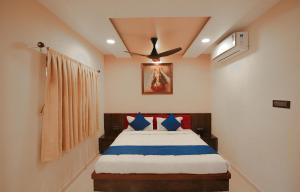 Schlafzimmer mit einem Bett mit blauen und roten Kissen in der Unterkunft Raaj Resort in Panvel