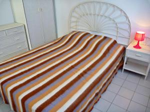 マルセイヤンにあるAppartement Marseillan-Plage, 2 pièces, 6 personnes - FR-1-387-102のストライプ毛布とテーブルの上にランプが備わるベッド