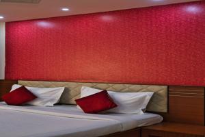 Un dormitorio con una pared roja y una cama con almohadas rojas. en Business inn, en Bangalore