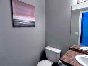 a bathroom with a toilet and a painting on the wall at Canadian Rockies Chalets in Canmore