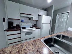 uma cozinha com electrodomésticos brancos e um lavatório em Canadian Rockies Chalets em Canmore