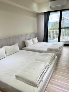 1 dormitorio con 2 camas y ventana grande en Lin House, en Checheng