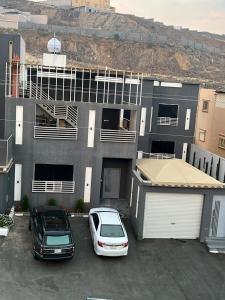 dos autos estacionados en un estacionamiento frente a un edificio en شاليه كريكت, en Abha