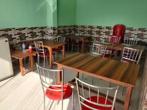un restaurante con mesas de madera y sillas rojas en Corbett Rejoice Home Stay, en Jhirna