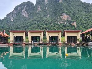 a group of buildings with a mountain in the background at Khaosok Eco Raft in Ban Kraison